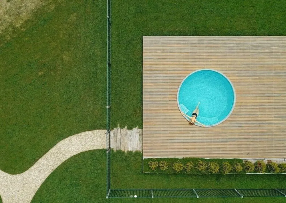 Aerial view of a round plunge pool set into a timber deck on a lawn