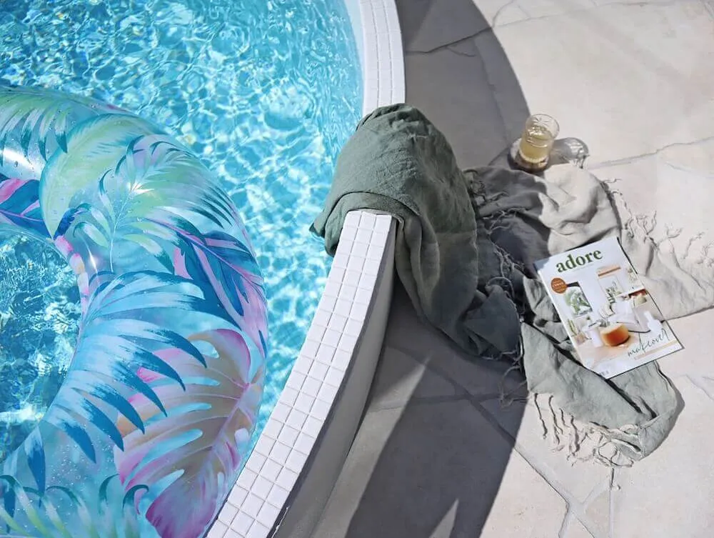 Edge of a round plunge pool with a towel and magazine