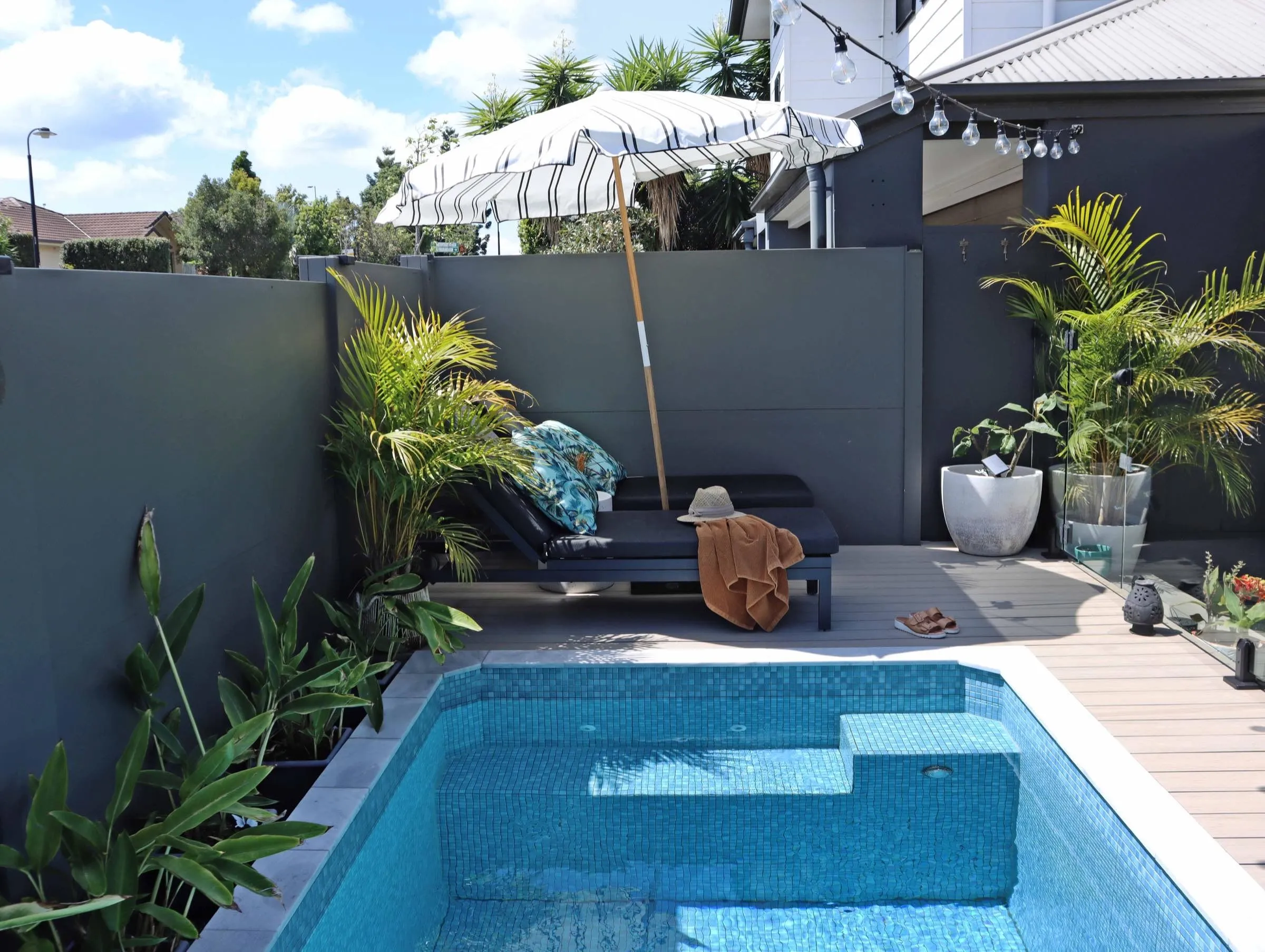 Rectangular plunge pool in a courtyard with lounges and an umbrella