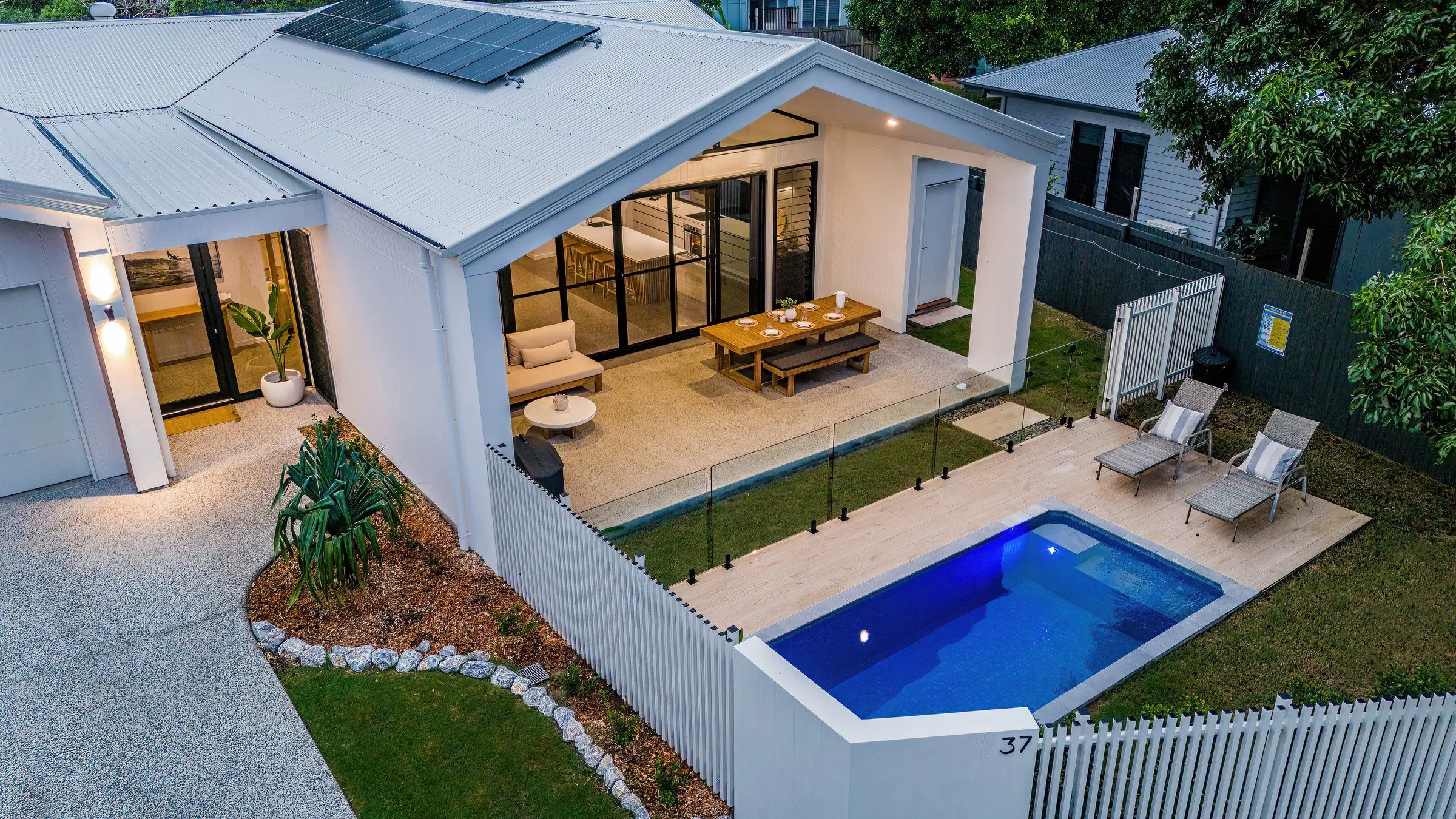 Rectangular plunge pool with glass fencing beside a home's covered alfresco area
