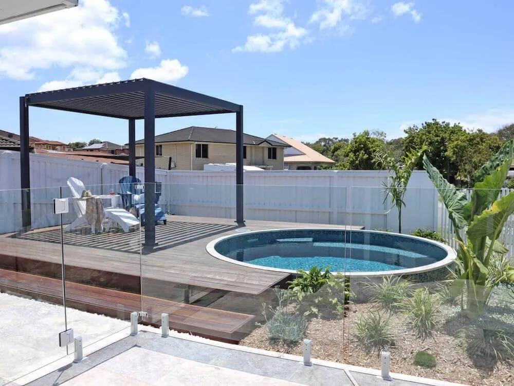 Round plunge pool on a deck under a black pergola