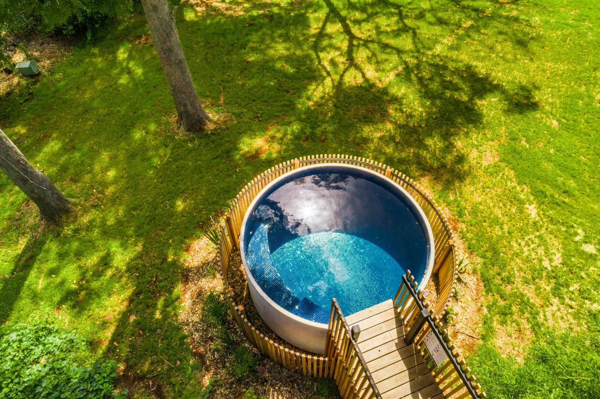 Aerial view of a round timber-clad plunge pool with steps in bushland