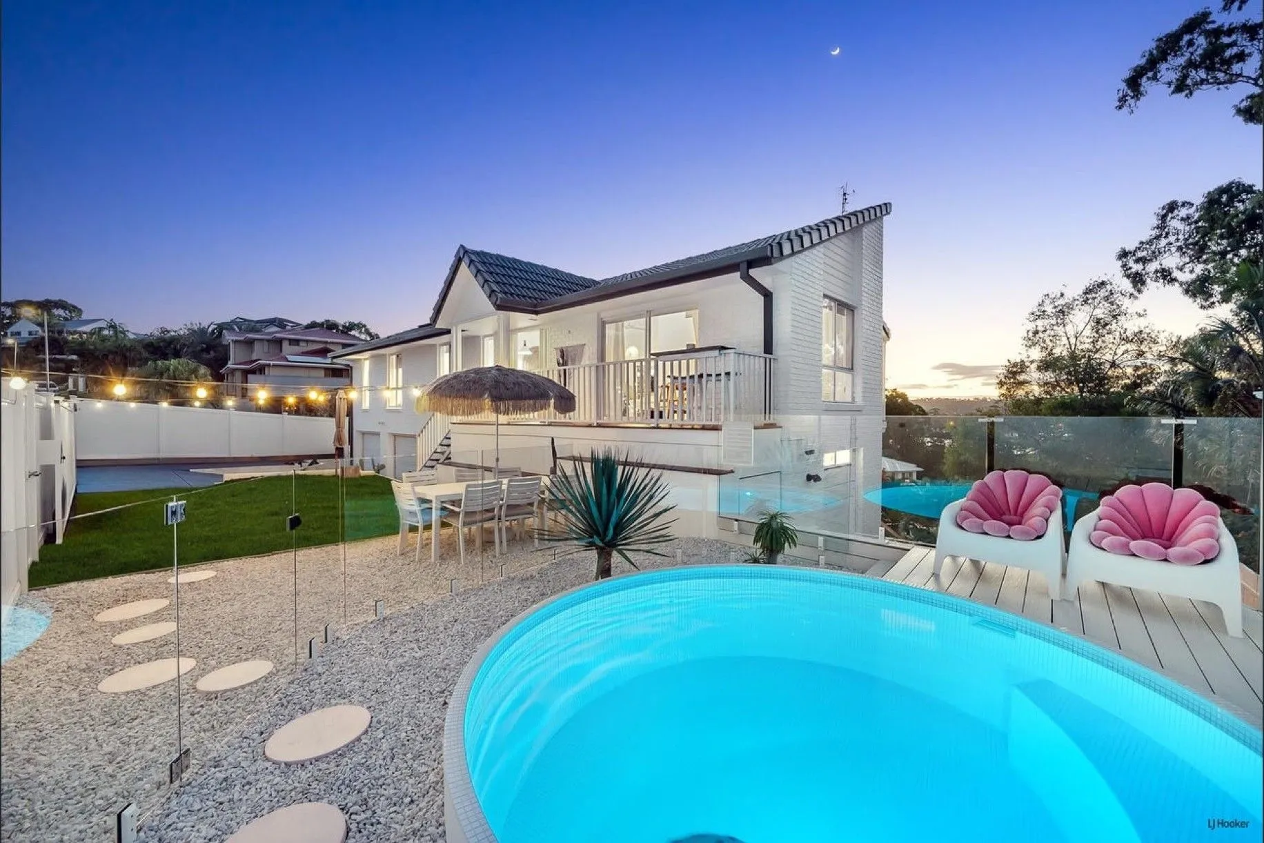 Round plunge pool glowing at dusk in a white courtyard