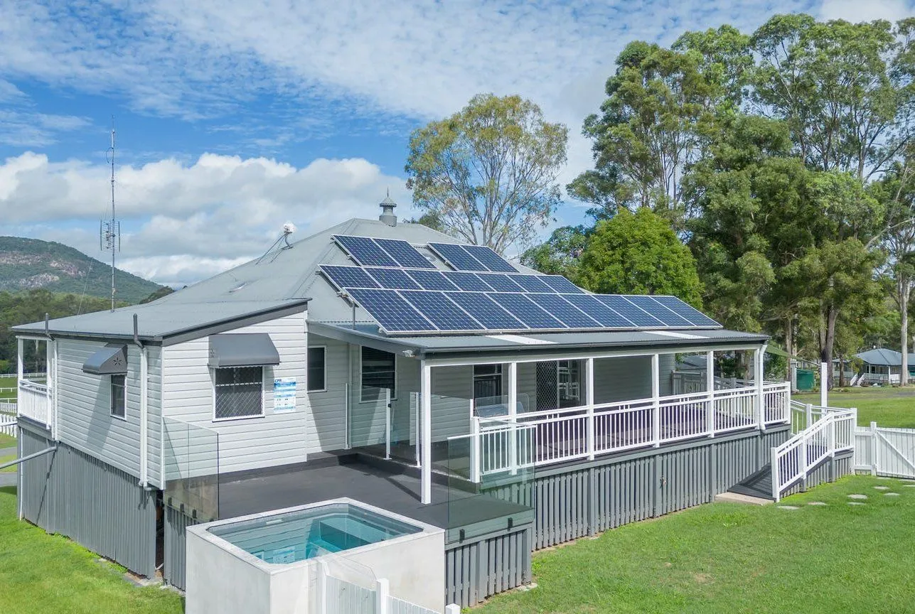 Square plunge pool beside a Queenslander home with a wraparound verandah