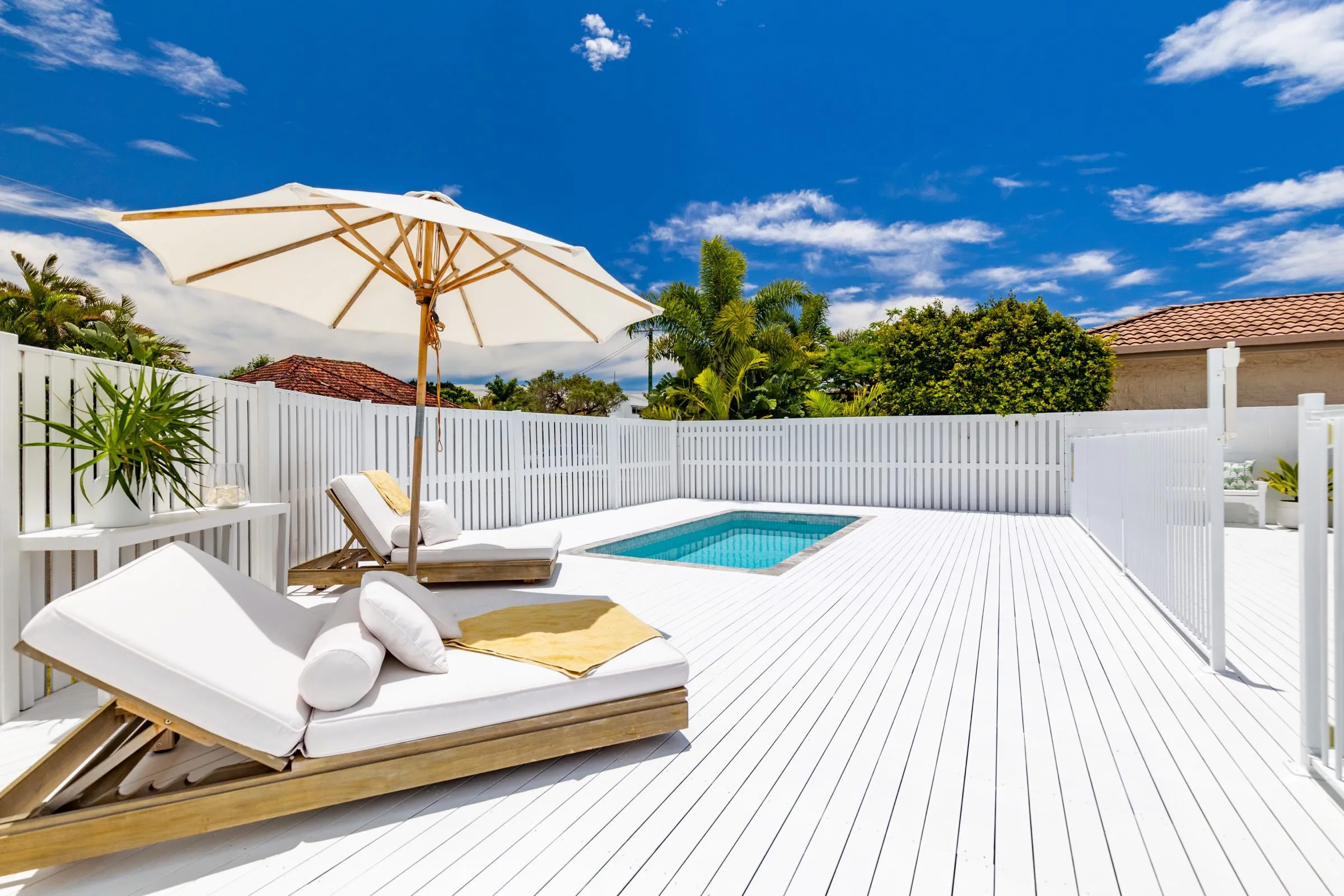 Small plunge pool on a white deck with sun lounges and an umbrella