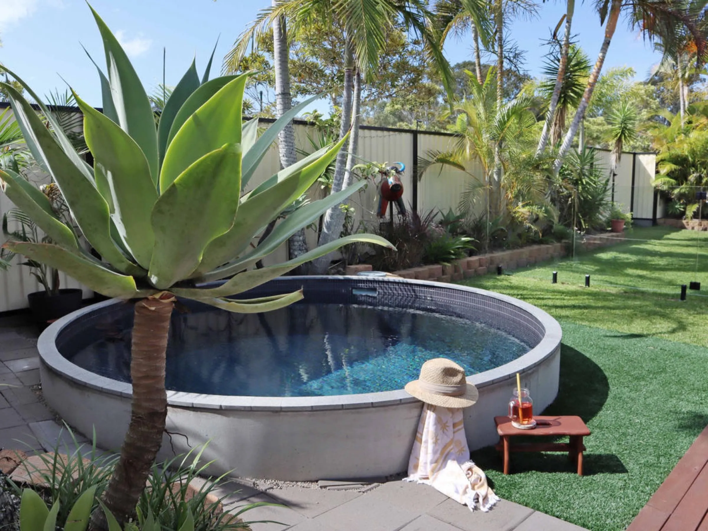 Round plunge pool in a garden with an agave and a timber step