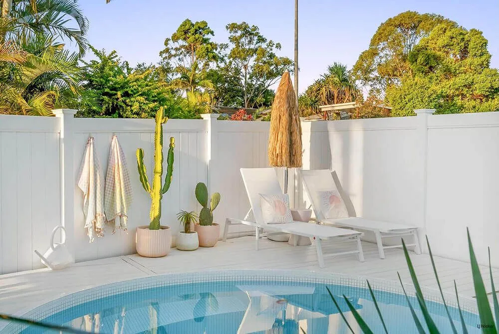 Round plunge pool in a white courtyard with cacti and sun lounges