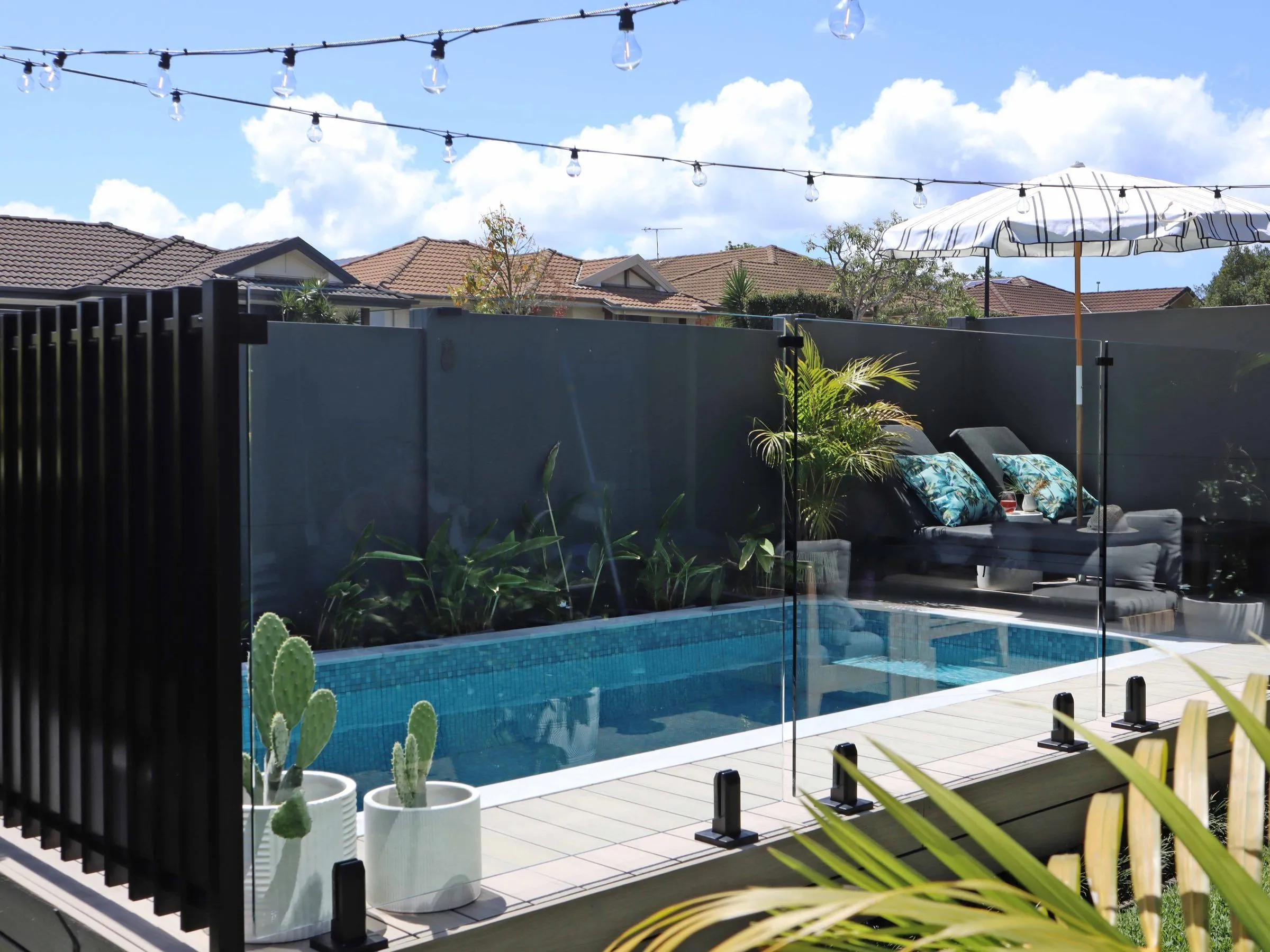 Rectangular plunge pool behind glass fencing in a dark-walled courtyard