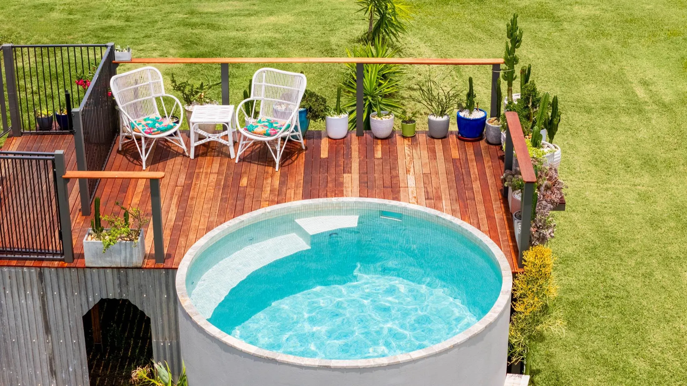 Round plunge pool set into a raised timber deck with outdoor chairs