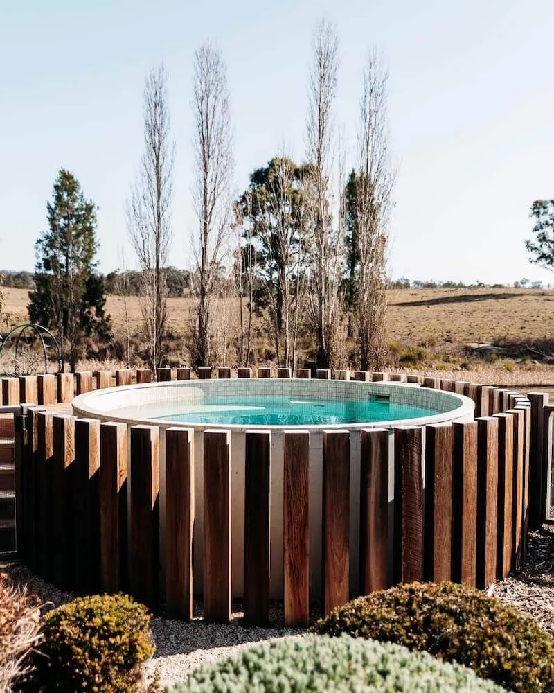 Round plunge pool clad in vertical timber in a rural setting