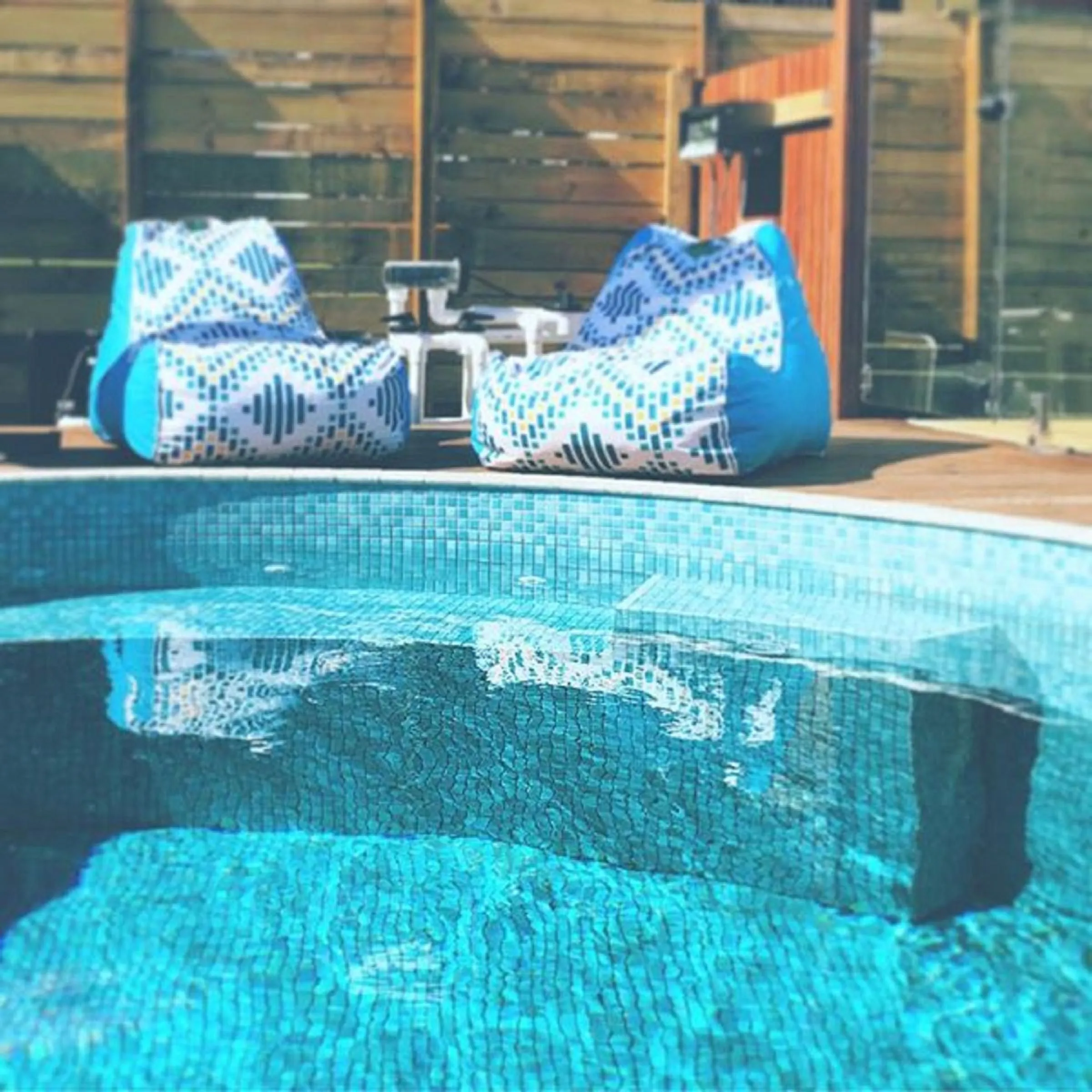Mosaic-tiled plunge pool in front of two blue bean bags