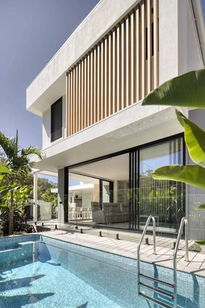 Rectangular plunge pool with a ladder beside a modern two-storey home