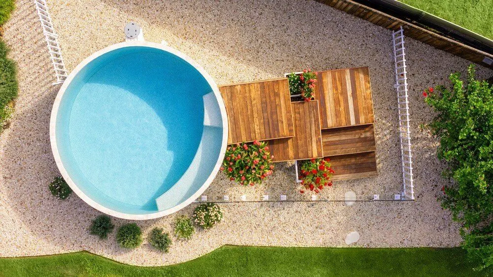 Aerial view of a round plunge pool beside a timber deck and gravel garden