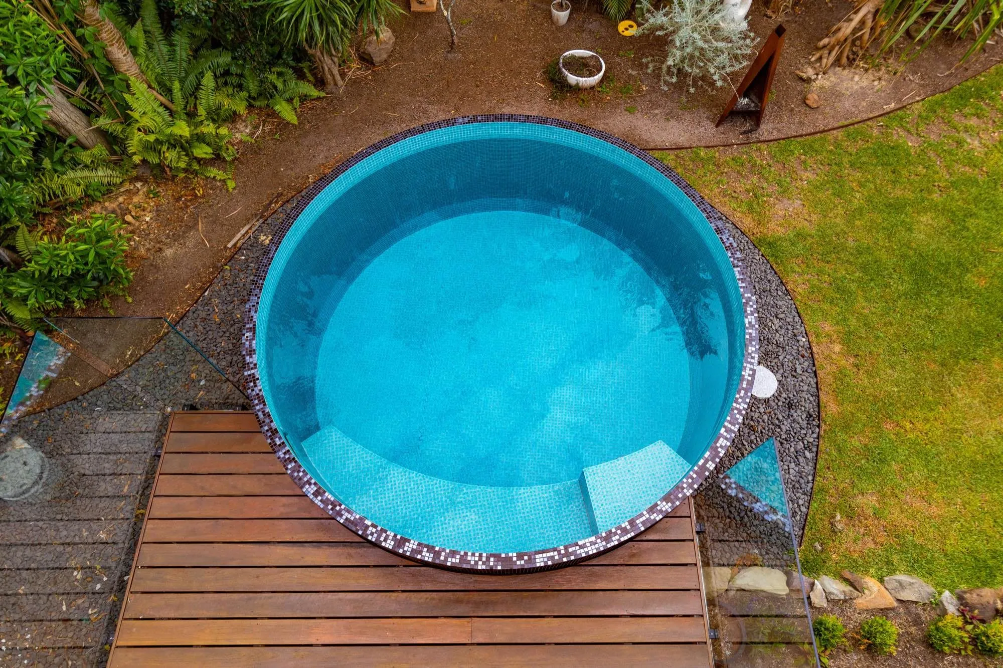 Aerial view of a round mosaic-tiled plunge pool beside a timber deck