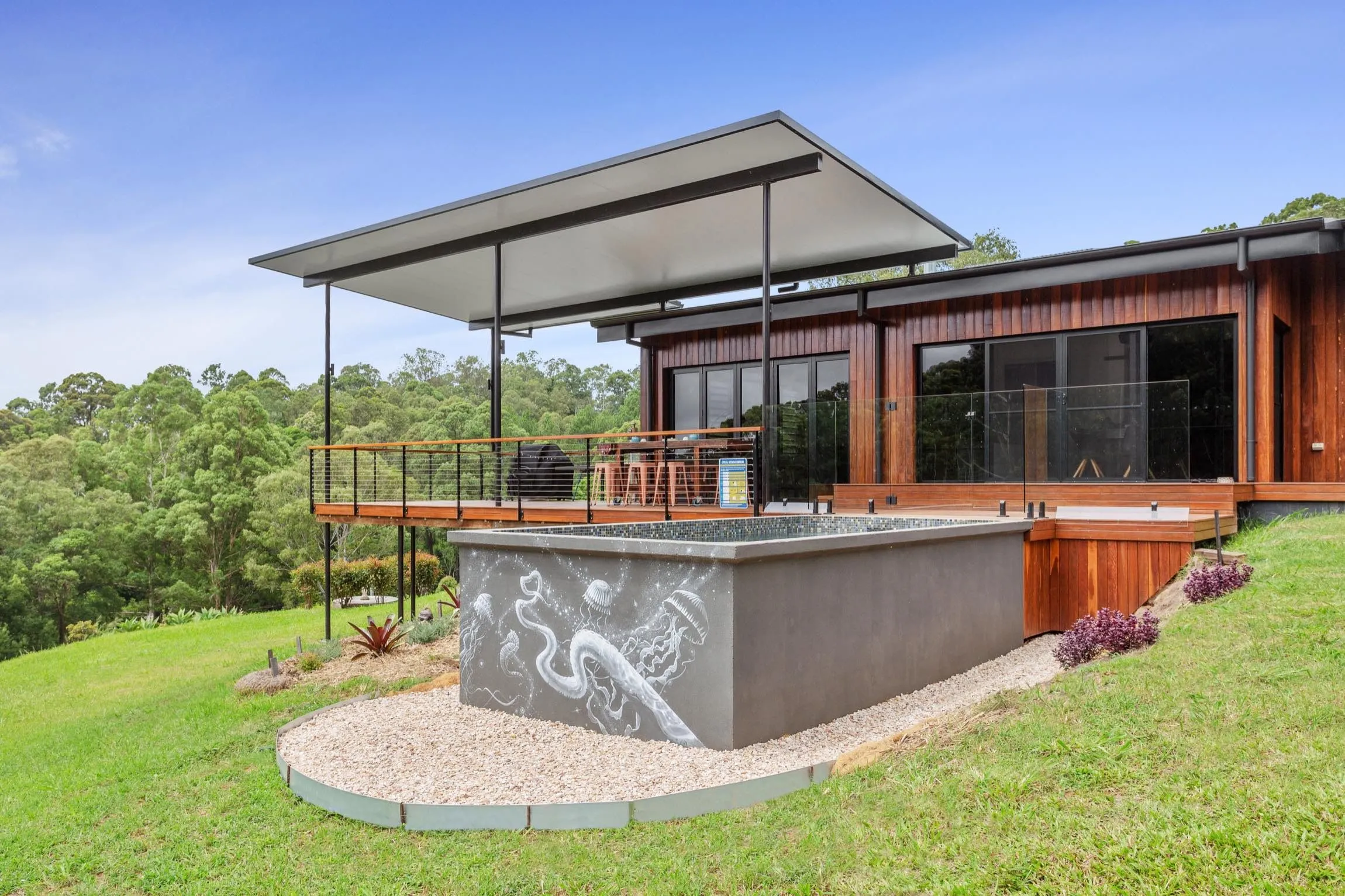 Plunge pool below an elevated deck and cabin on a sloping block