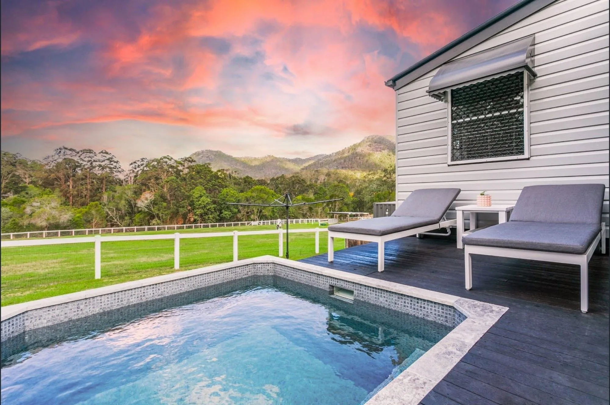 Plunge pool beside a deck with sun lounges at sunset