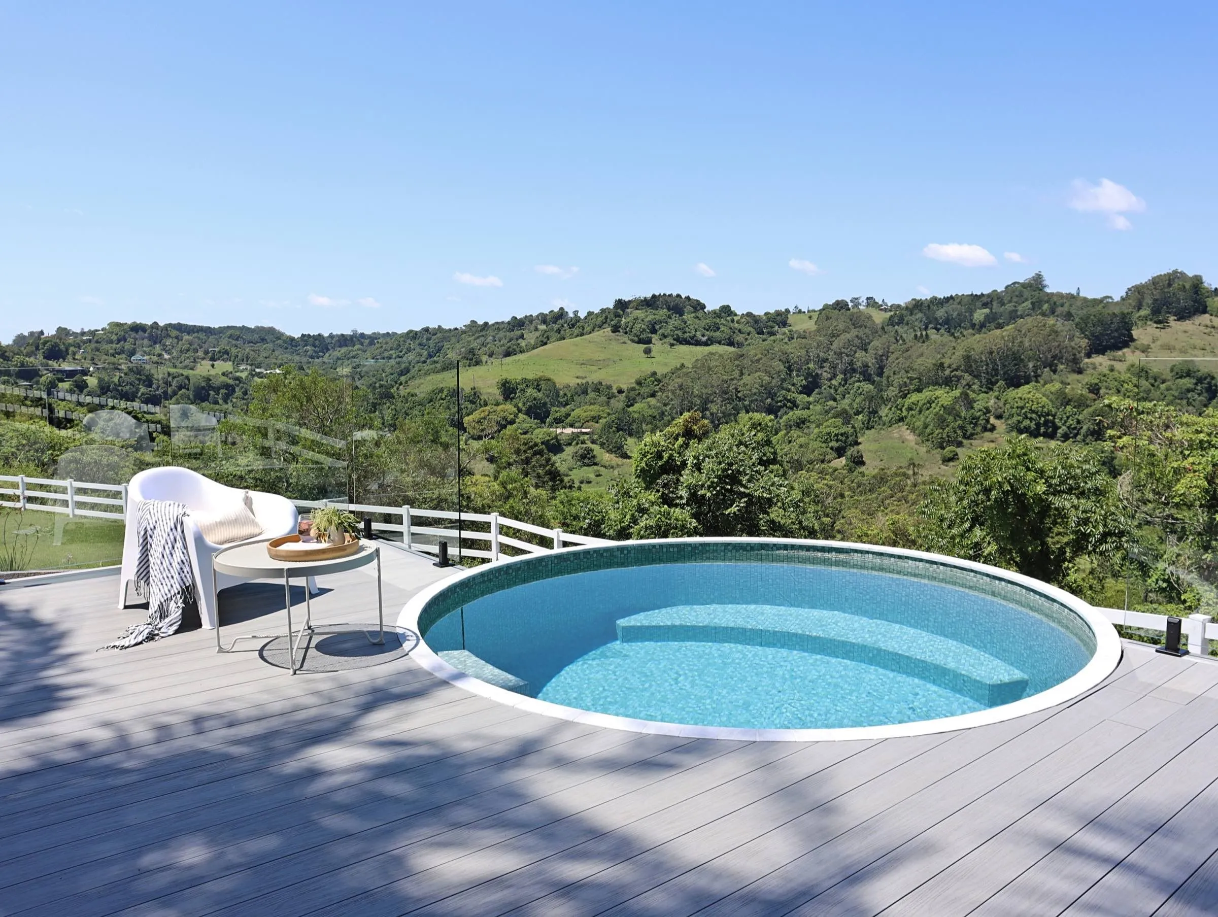 A round tiled plunge pool on an elevated deck overlooking a hinterland valley