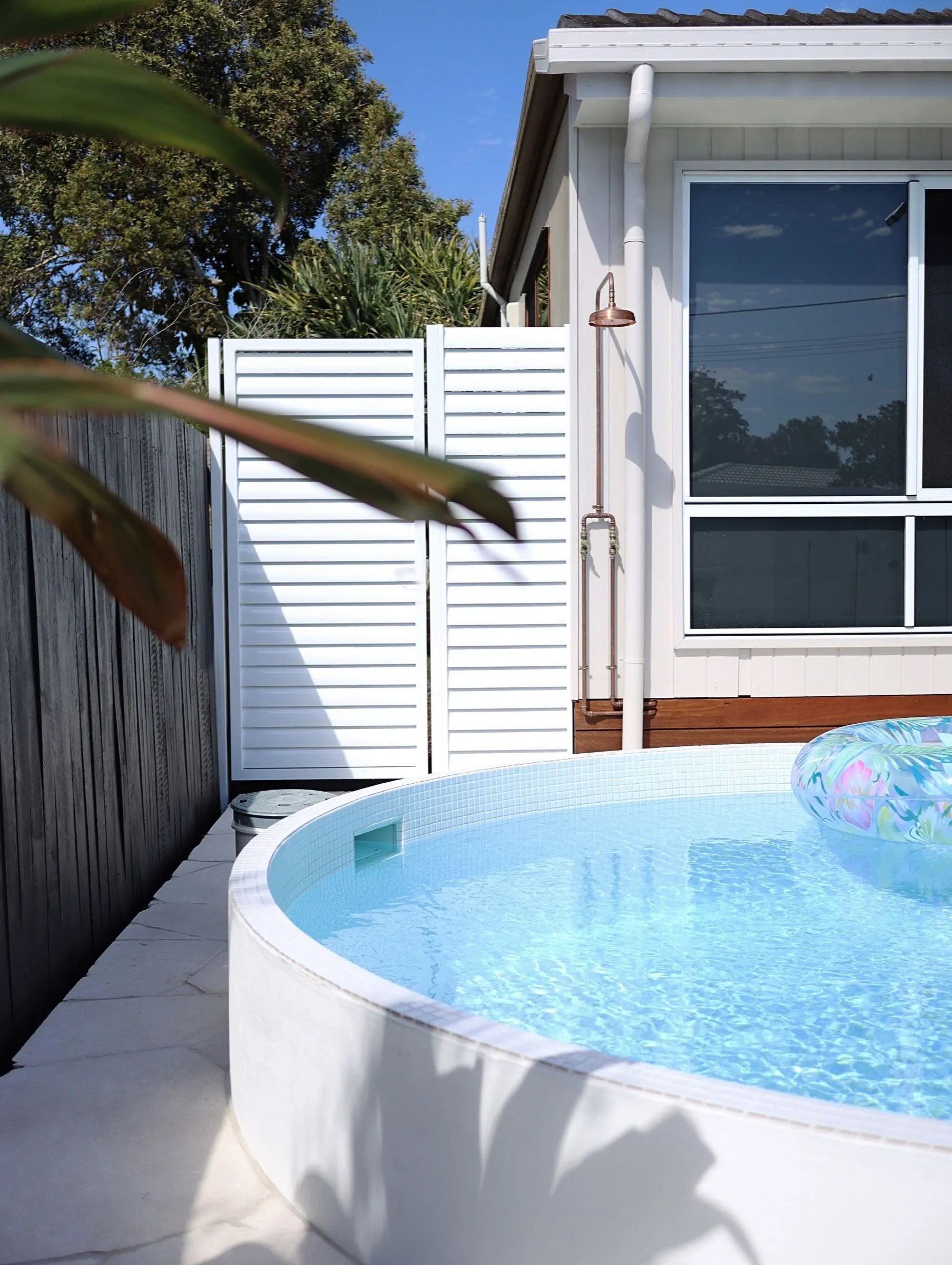 Round plunge pool in a narrow side yard beside an outdoor shower