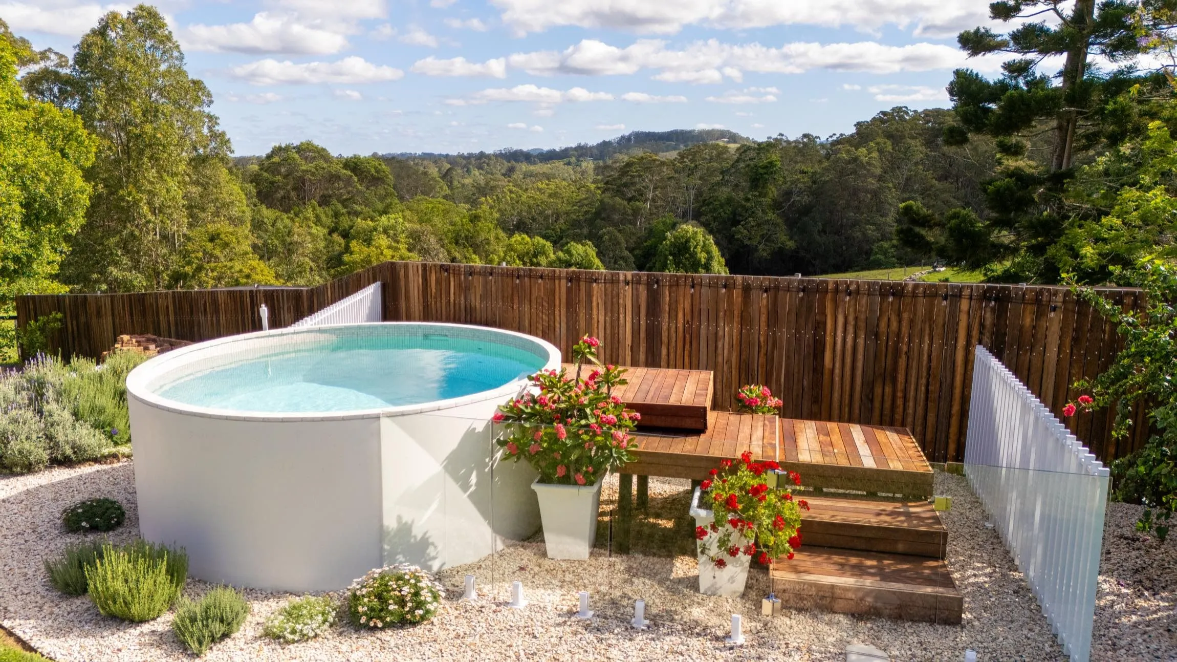 Round plunge pool beside a timber bench in a landscaped garden