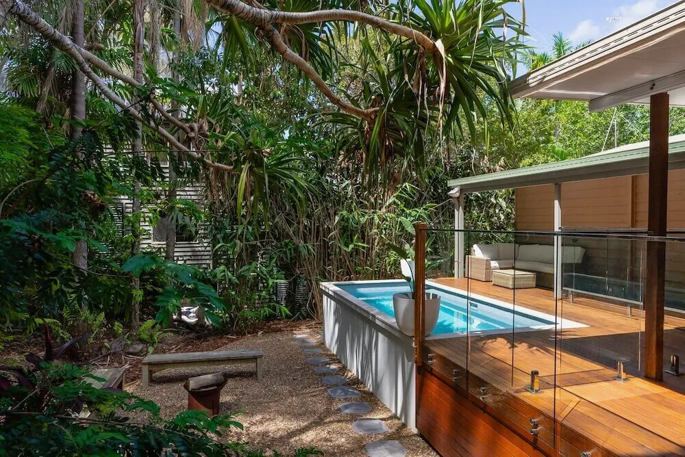 Rectangular plunge pool on an elevated deck in a leafy garden