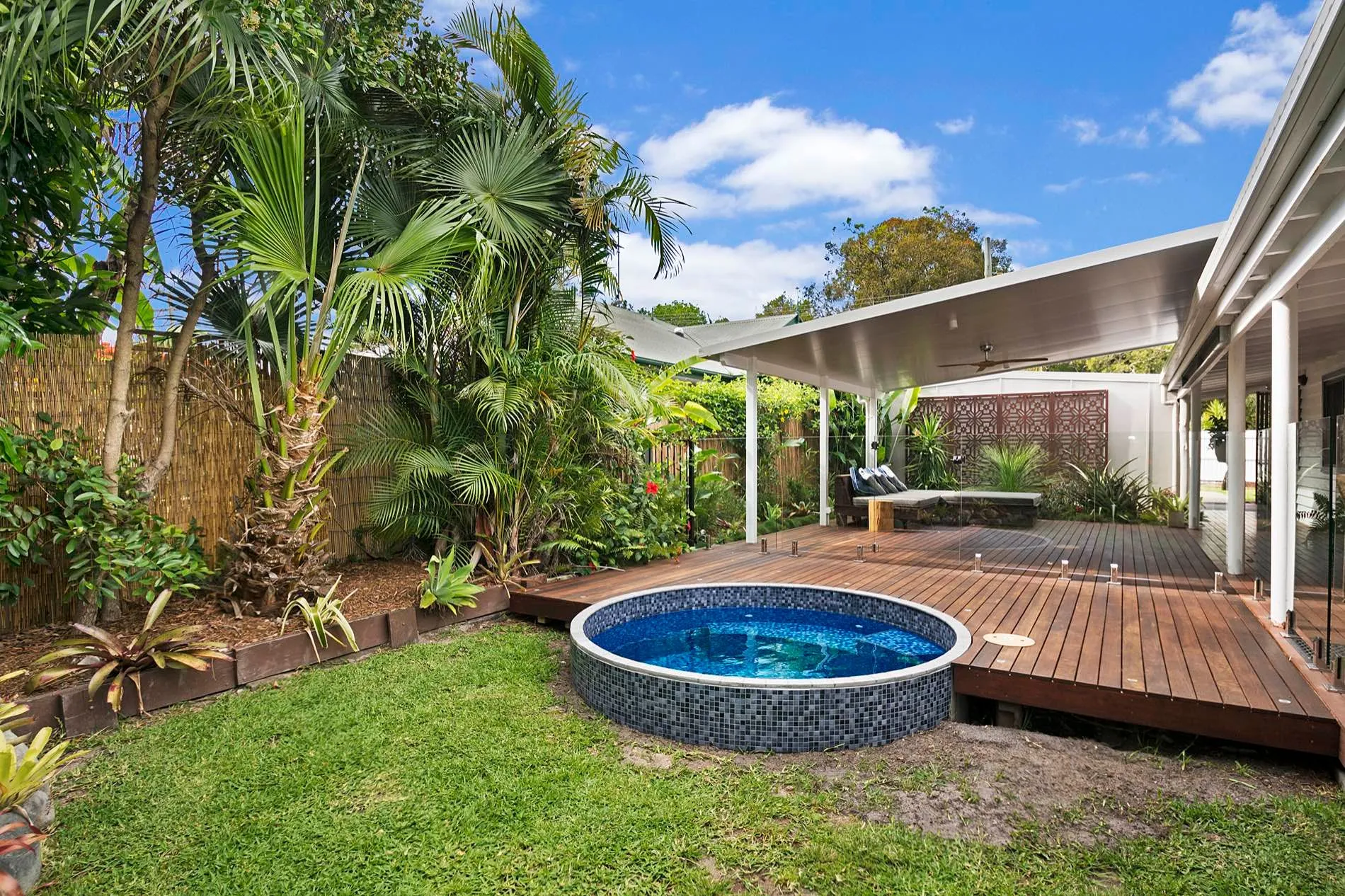 Round plunge pool set into a timber deck in a tropical garden