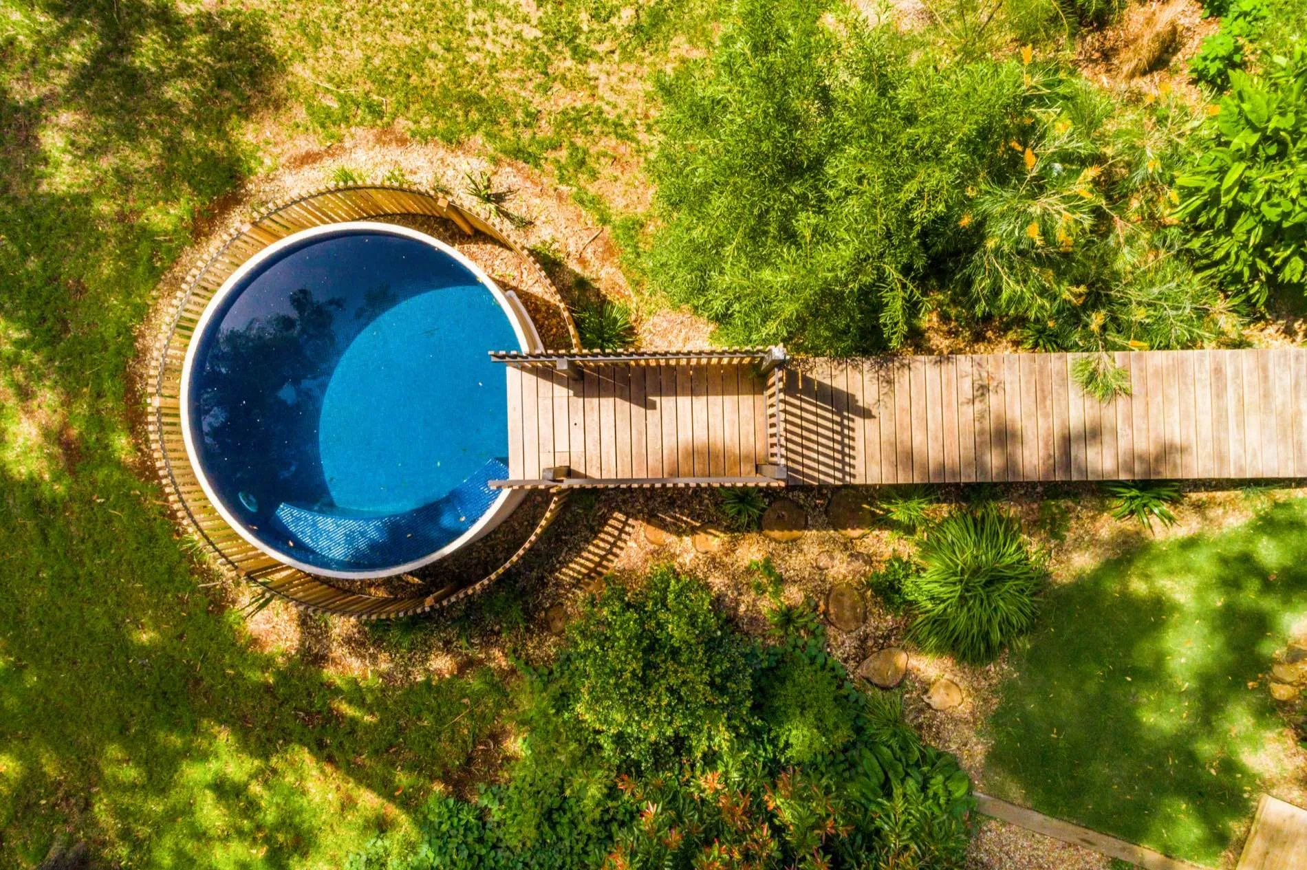 Aerial view of a round plunge pool and timber boardwalk in bushland