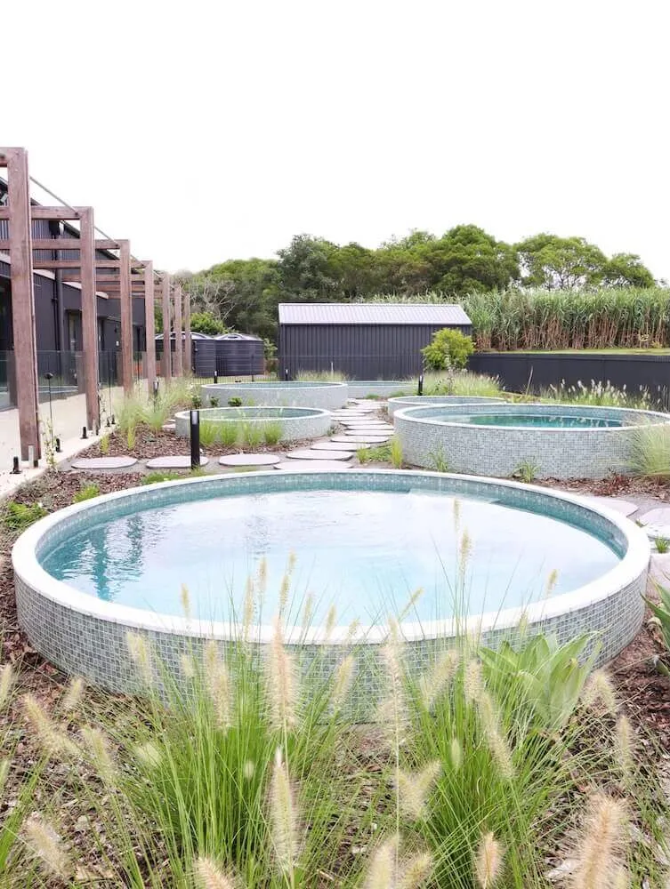 Round mosaic-tiled plunge pool among ornamental grasses