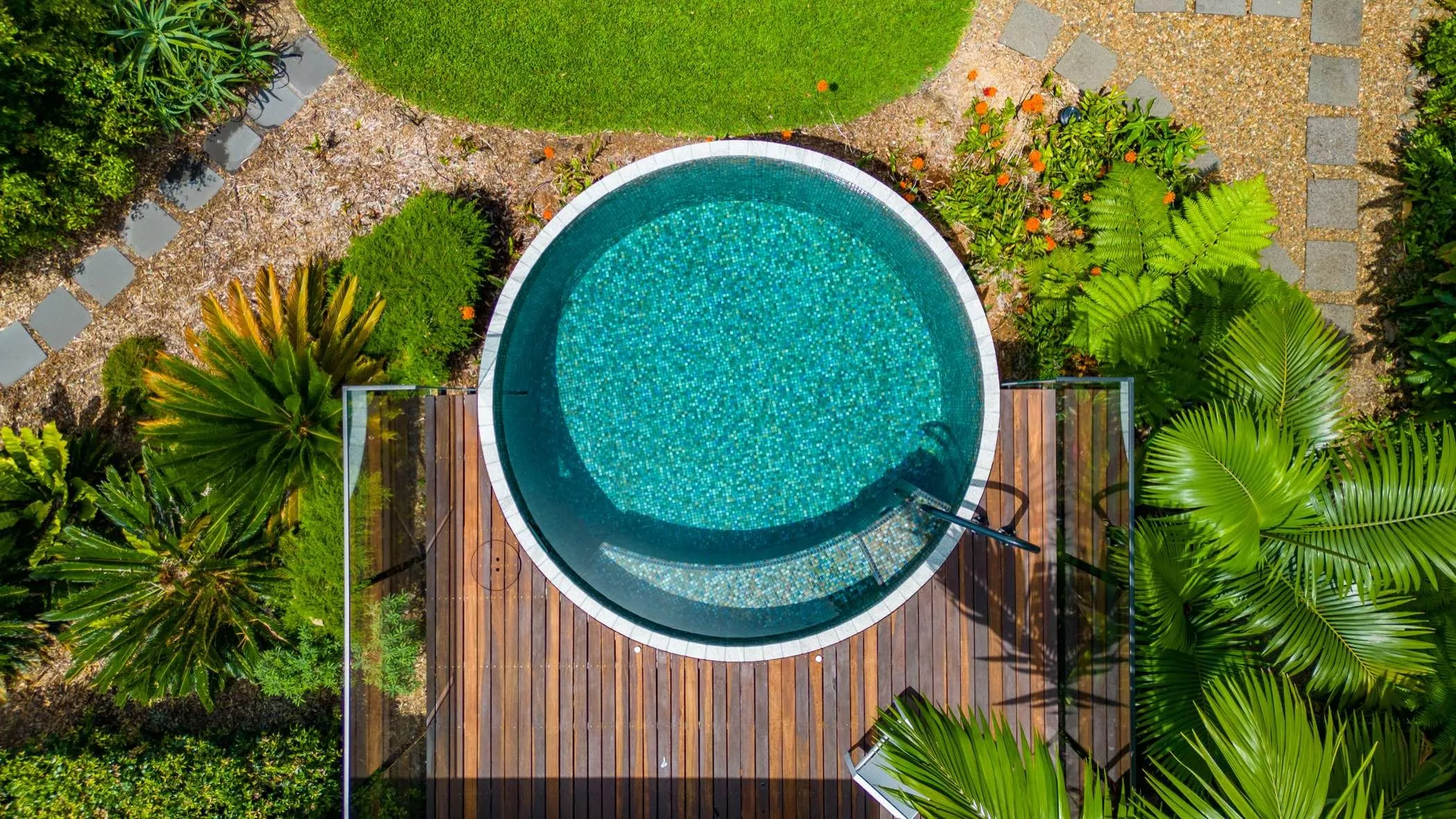 An aerial view of a round tiled plunge pool set in a lush garden
