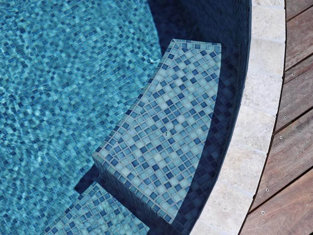 Close-up of blue mosaic tiles and the seat inside a plunge pool