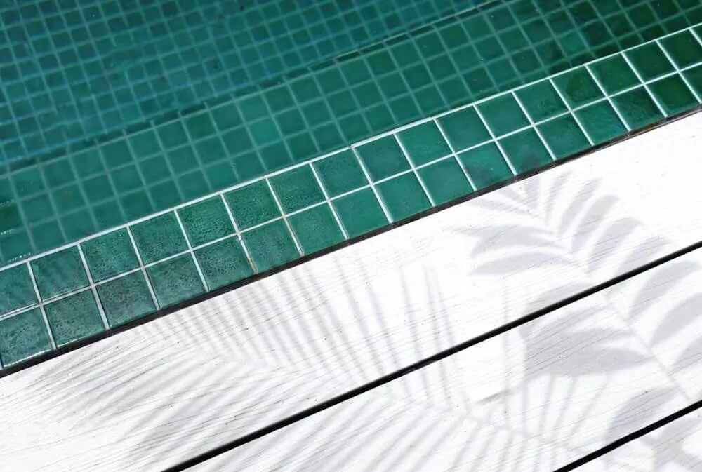 Close-up of green pool tiles against a white timber deck