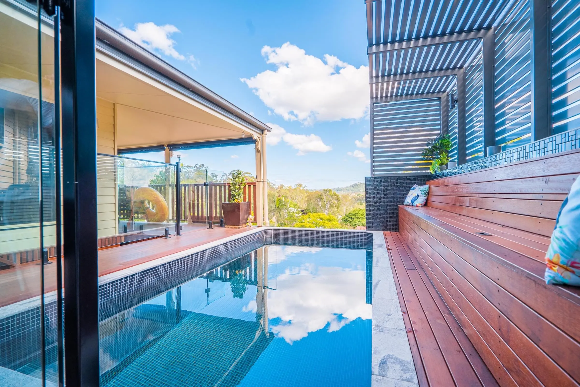 Narrow plunge pool beside a timber deck, reflecting the sky
