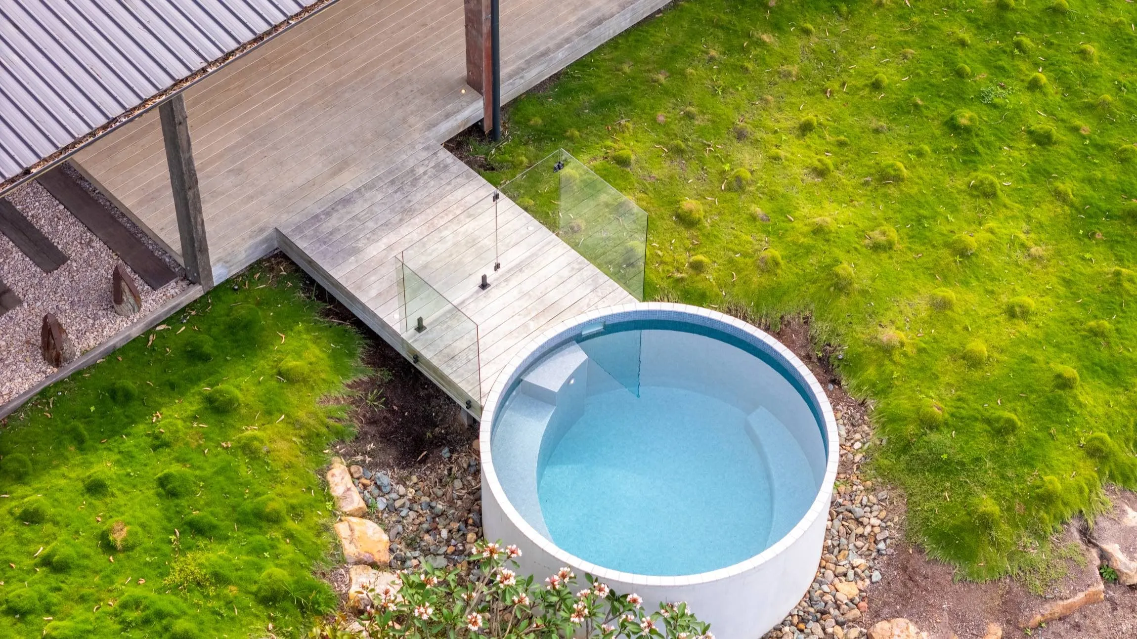 Round plunge pool beside a timber boardwalk on a grassy slope